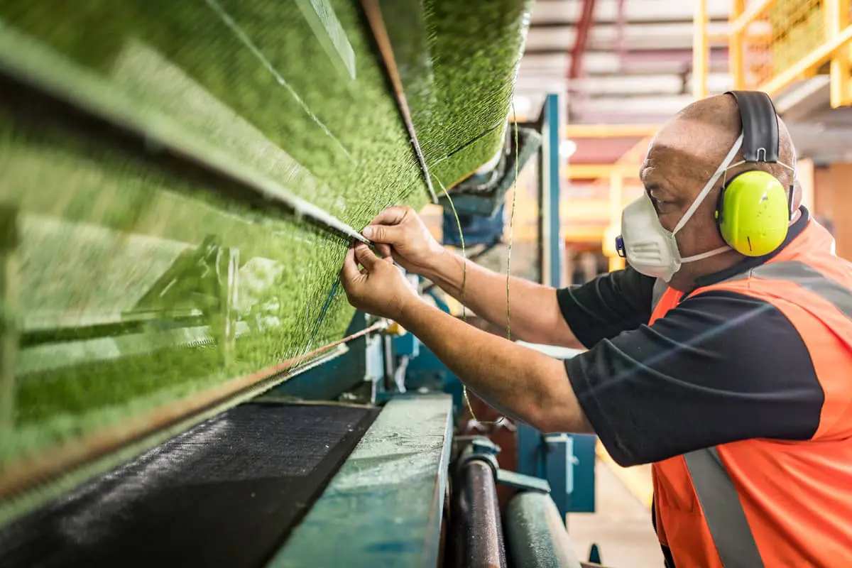 Man checking the Quality Synthetic Grass is Made